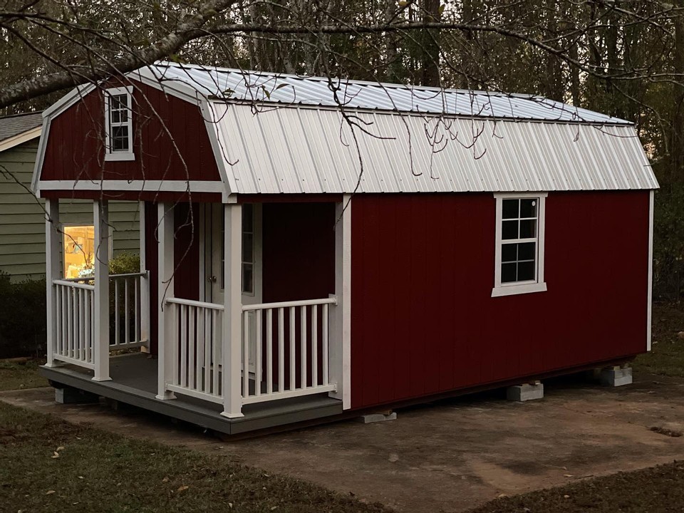 A shed with red siding and white roof and porch by Westwood Sheds.